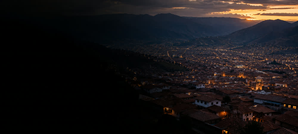 Vista aérea de Cusco al anochecer, con los tejados descendiendo hacia el valle